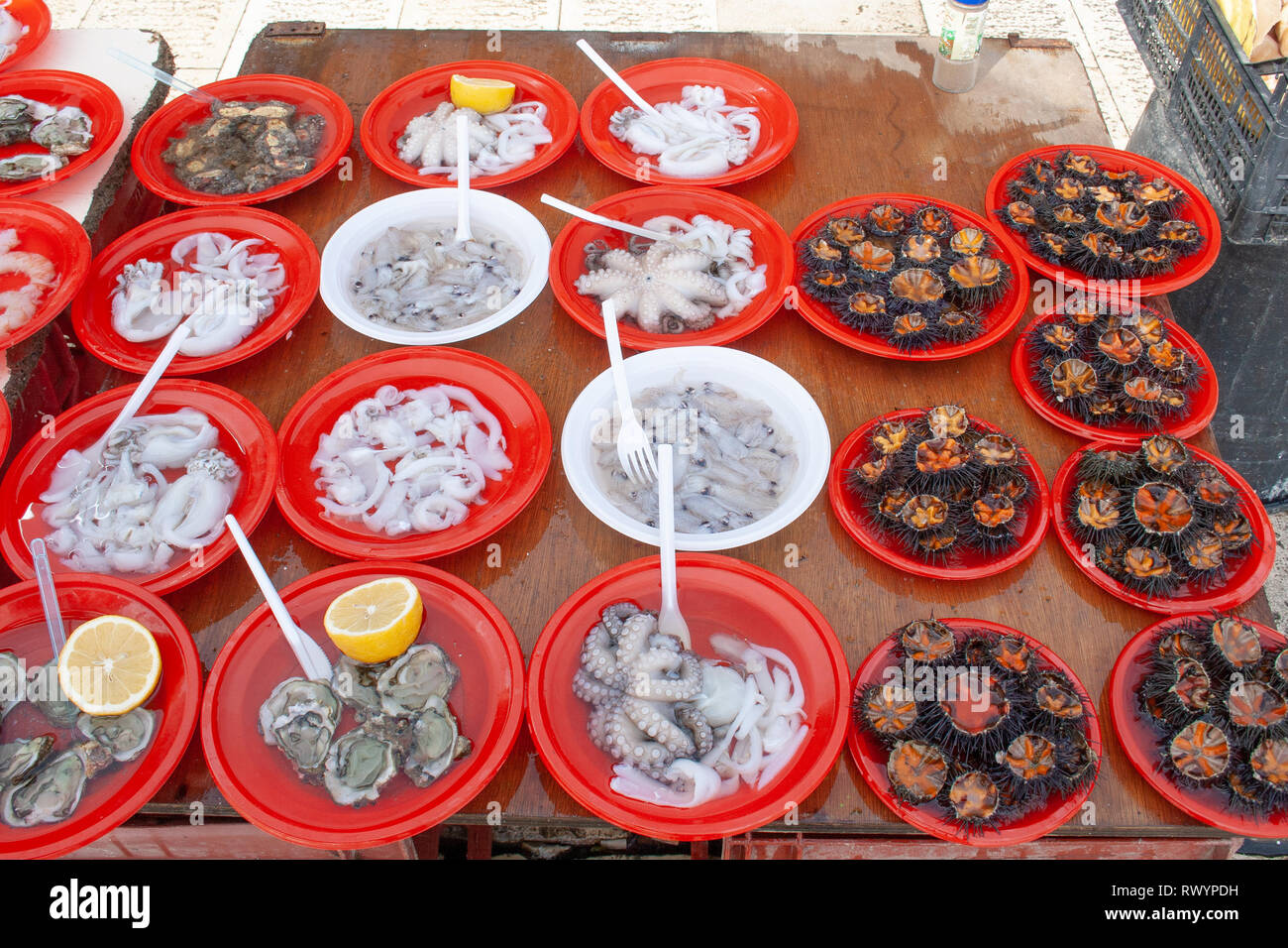 Open air street food fish market on Bari promenade with raw fresh sushi ready to eat: shrimp, oyster, sea urchin, cuttlefish, squid, octopus Stock Photo