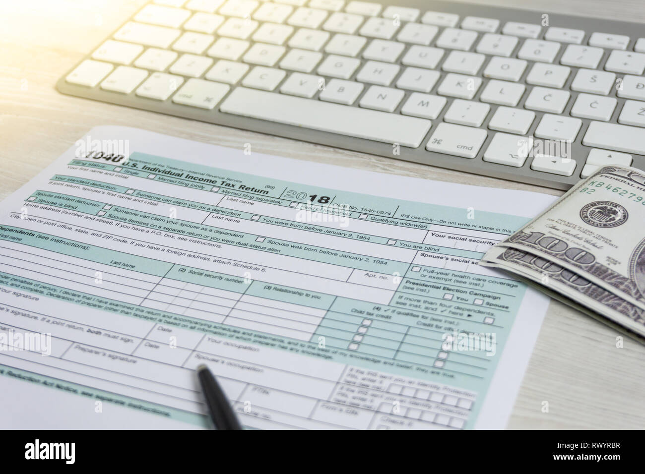 US tax form next to computer keyboard and tax form 1040. tax form us business income office hand fill concept Stock Photo