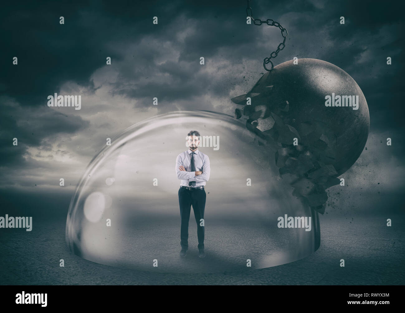 Businessman safely inside a shield dome during a storm that protects him from a wrecking ball. Protection and safety concept Stock Photo