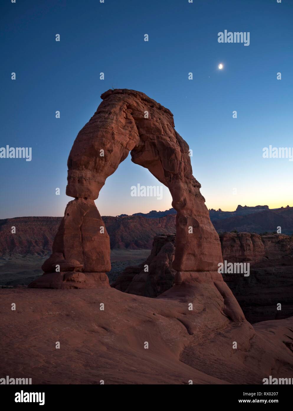 Delicate Arch rock arch Evening sky with moon, Arches National Park, Moab, Utah, USA Stock Photo