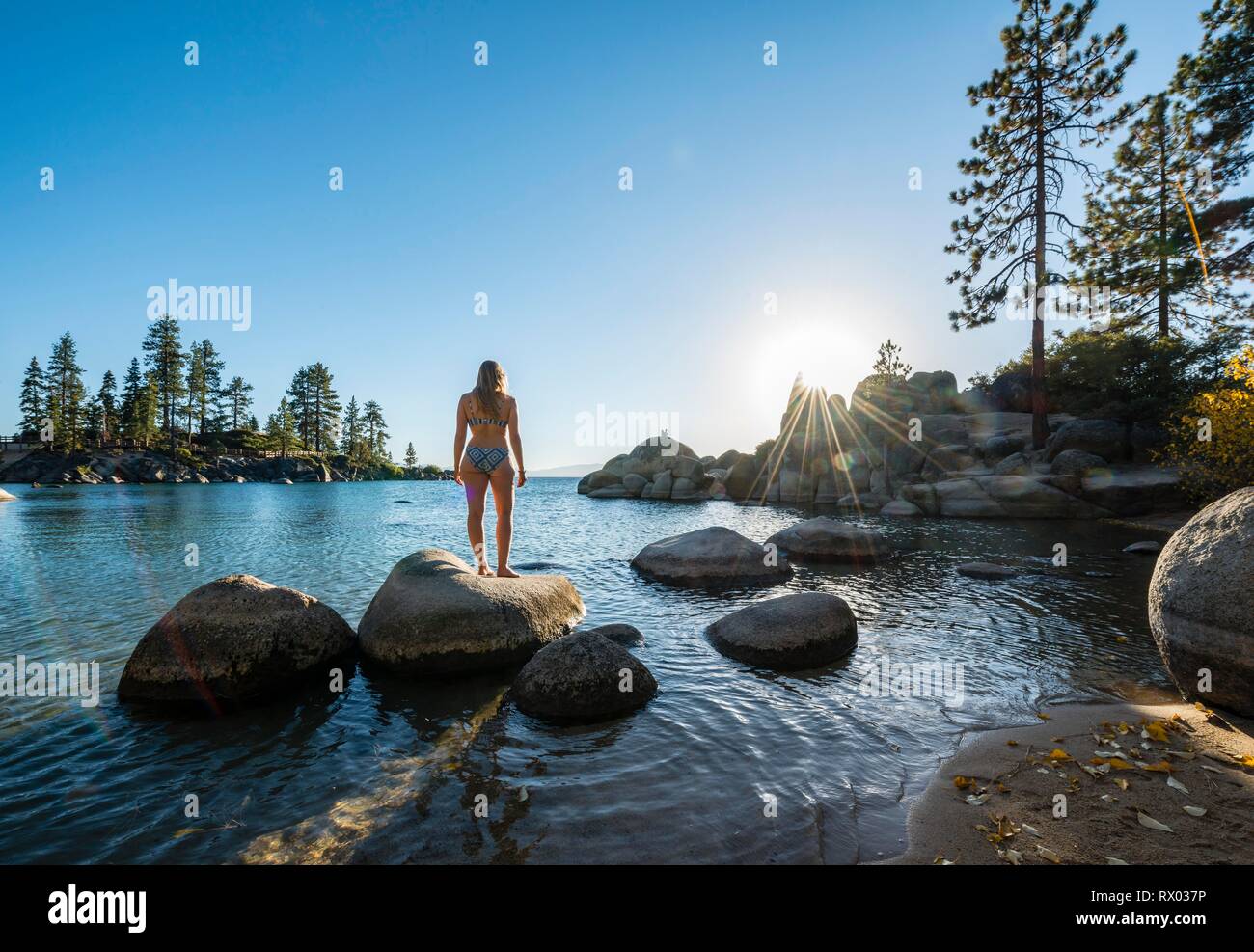 Young woman in bikini standing on a round stone in the water, bay at lake Lake Tahoe, Sand Harbor State Park, shore, California Stock Photo