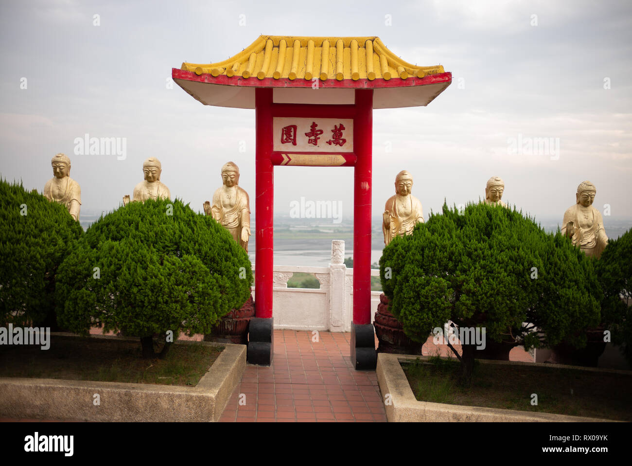 Fo Guang Shan - Largest Buddhist Monastery in Taiwan - A row of golden Buddhas behind bushes with a gateway. Kaohsiung, Taiwan Nov 2018 Stock Photo