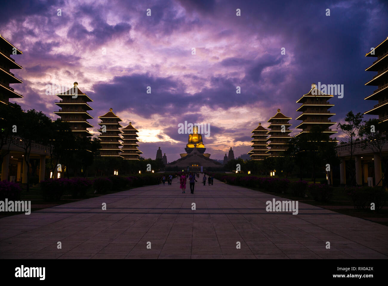 Fo Guang Shan - Largest Buddhist Monastery in Taiwan -  The enormous Shakyamuni Buddha at the end of a path of tourists under a dramatic sunset sky Stock Photo