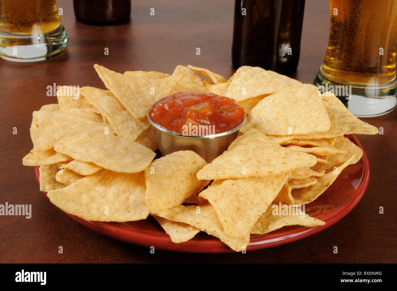 tortilla chips with salsa and glasses of beer on a bar counter Stock Photo