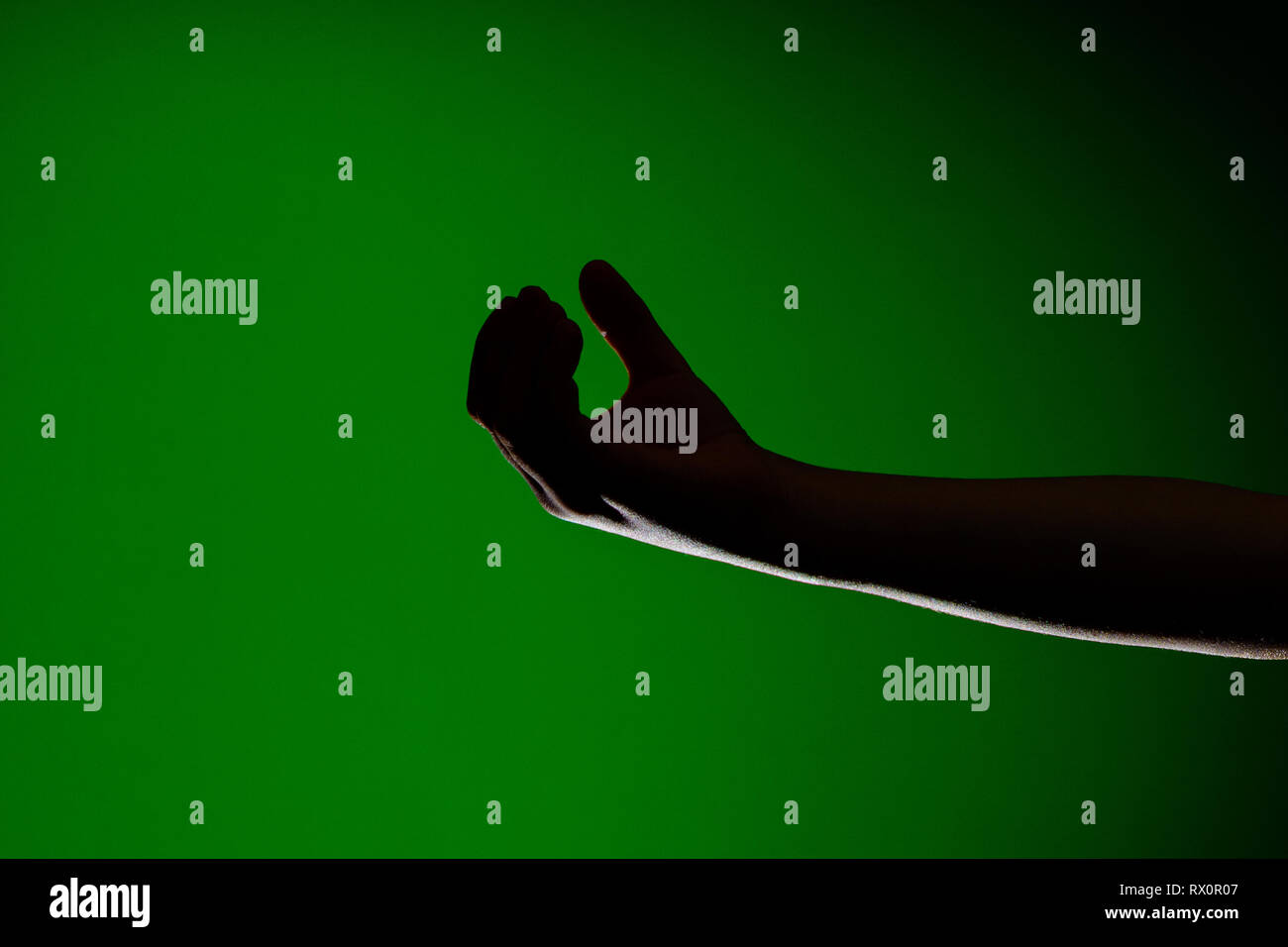 The shadow of the hand is isolated on a green background, which ...