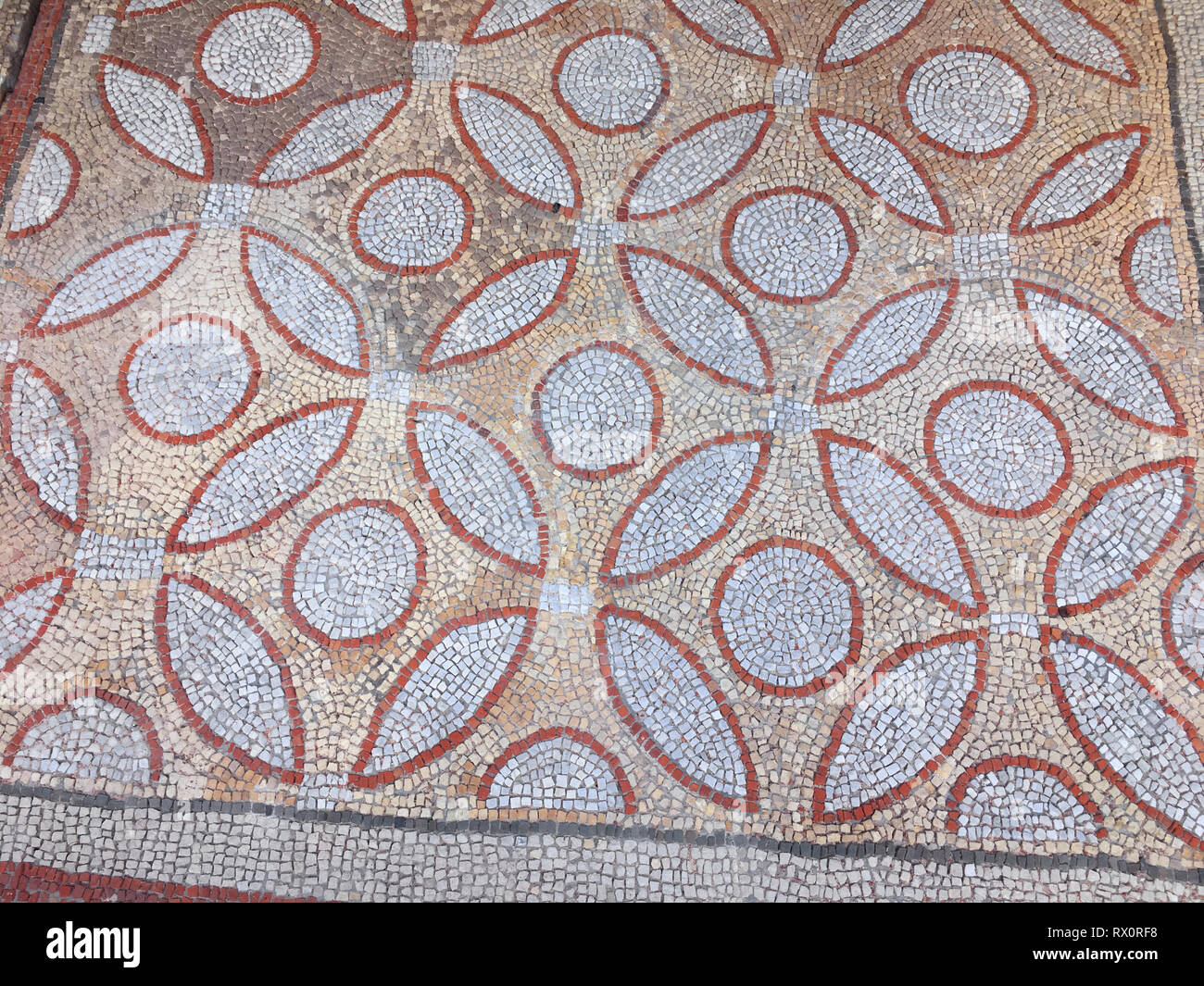 Fragment of an ancient floor mosaic. Colorful small tiles, unusual geometric ornament, floral and regular forms. Crimea Hersones Stock Photo