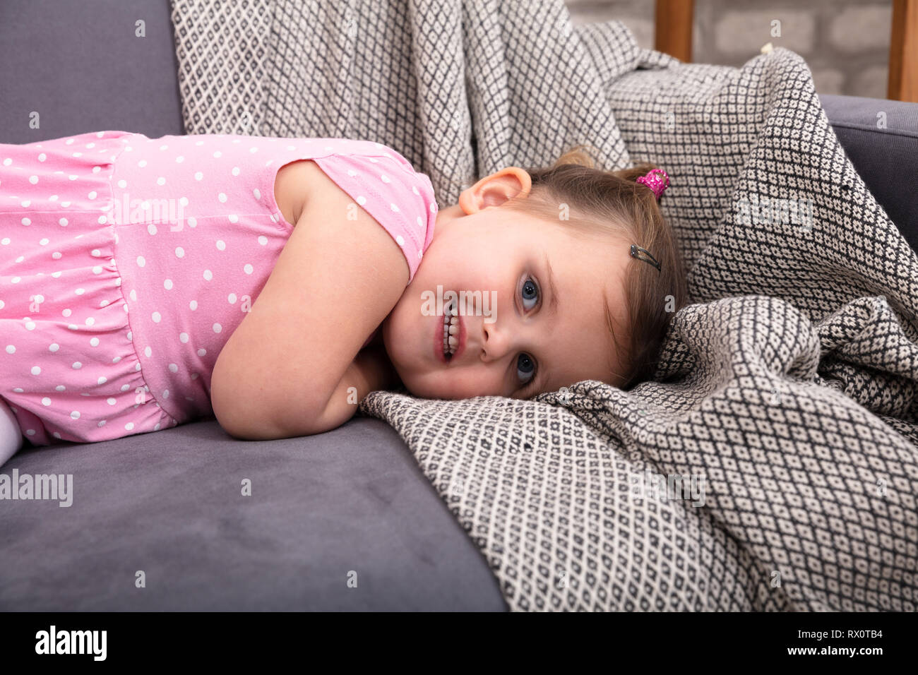 Smiling Little Girl Lying On Sofa At Home Stock Photo - Alamy