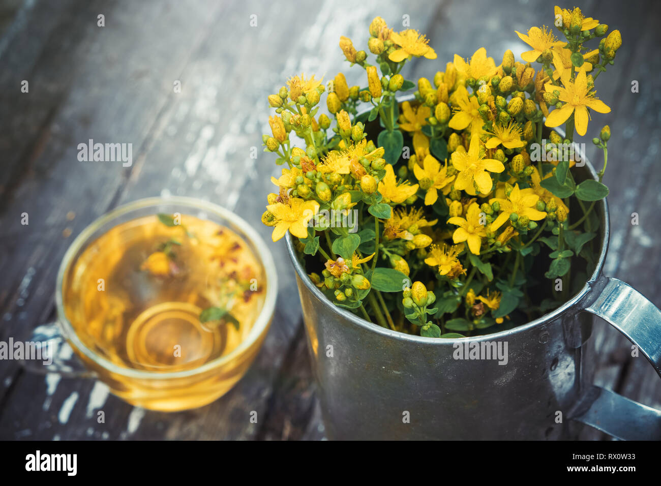 St Johns wort flowers in a large retro mug and Healthy hypericum tea - not in focus. Top view. Stock Photo
