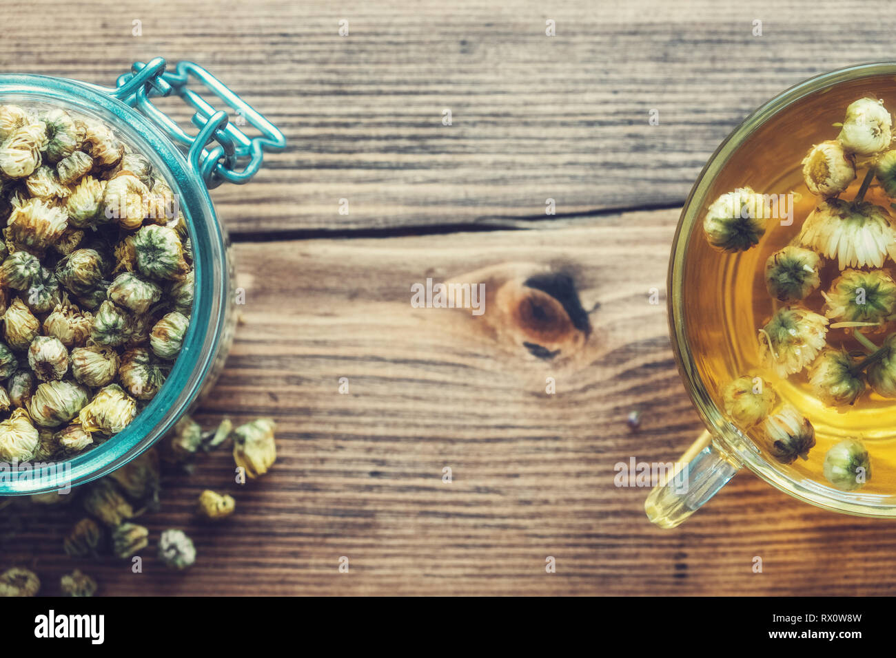 Healthy chamomile tea cup and glass jar of dry daisy flowers. Top view ...