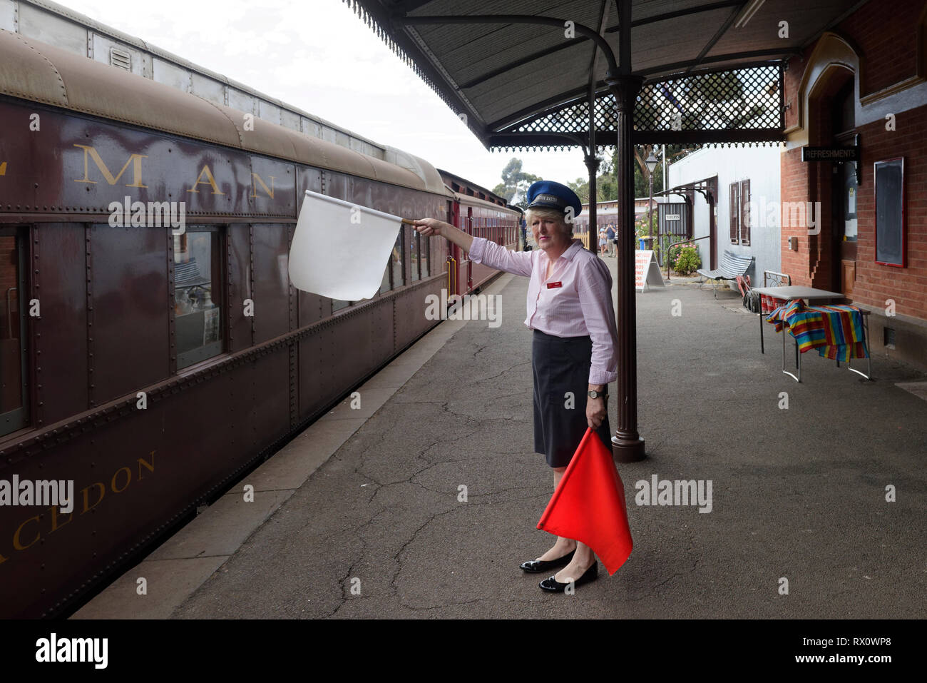 Station master with flags, railway station platform, Maldon, Victoria, Australia. Opened in 1884, the historic station served a vital role in supporti Stock Photo