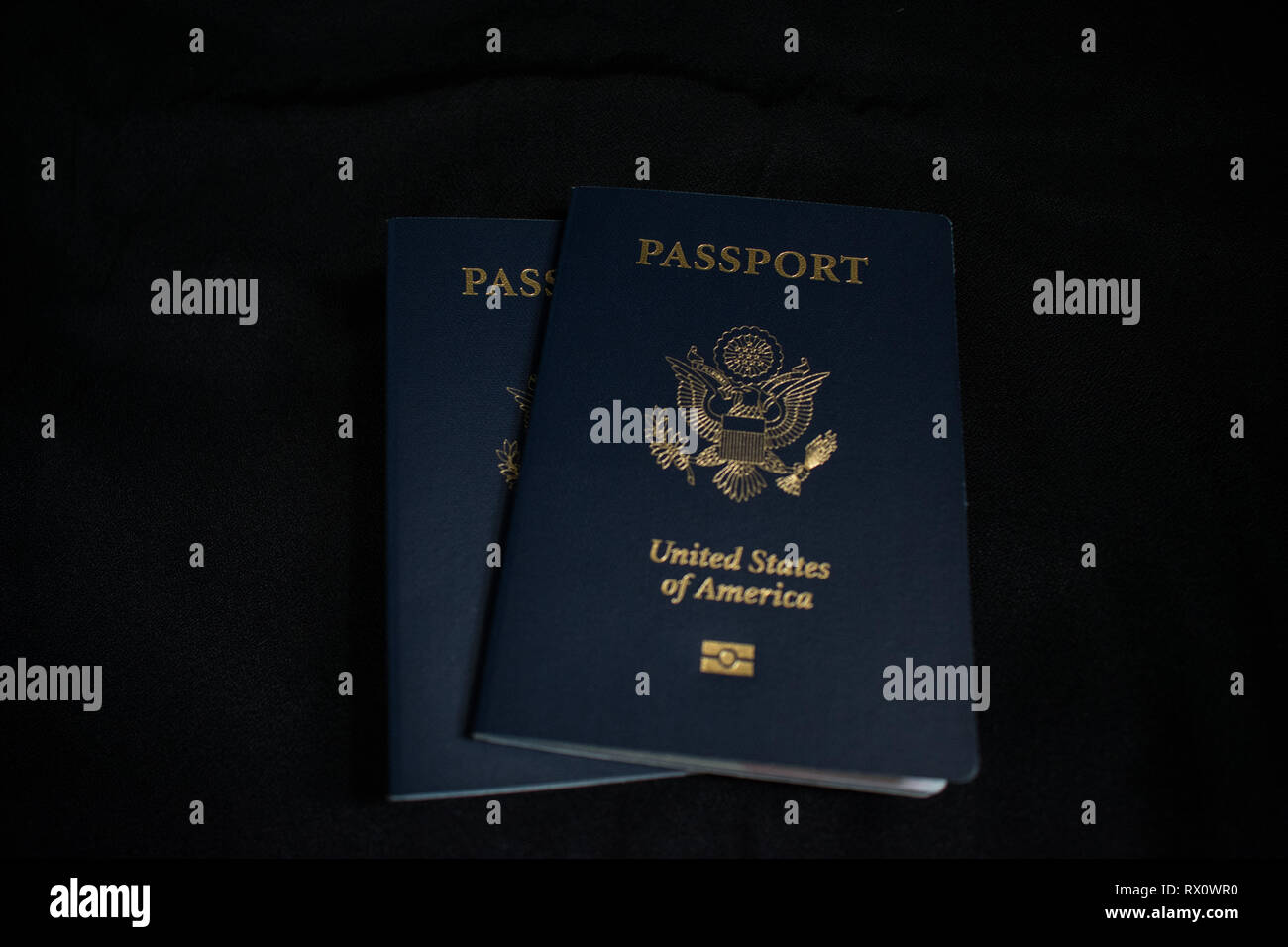 Two US passports centered on a black background Stock Photo