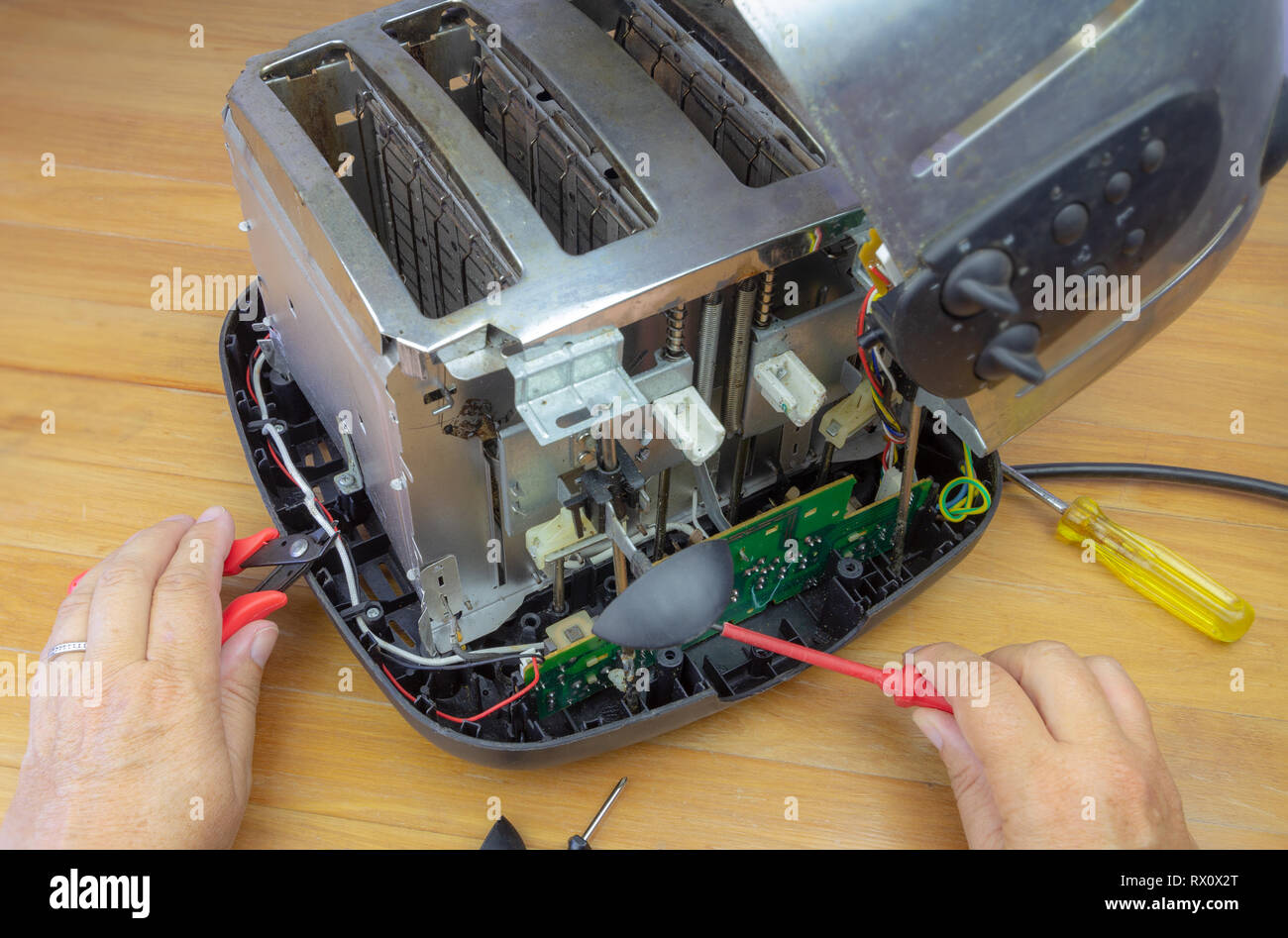 Concept Right to Repair, image showing hands of consumer repairing toaster with tools. Reduce waste by repairing household appliances. Stock Photo