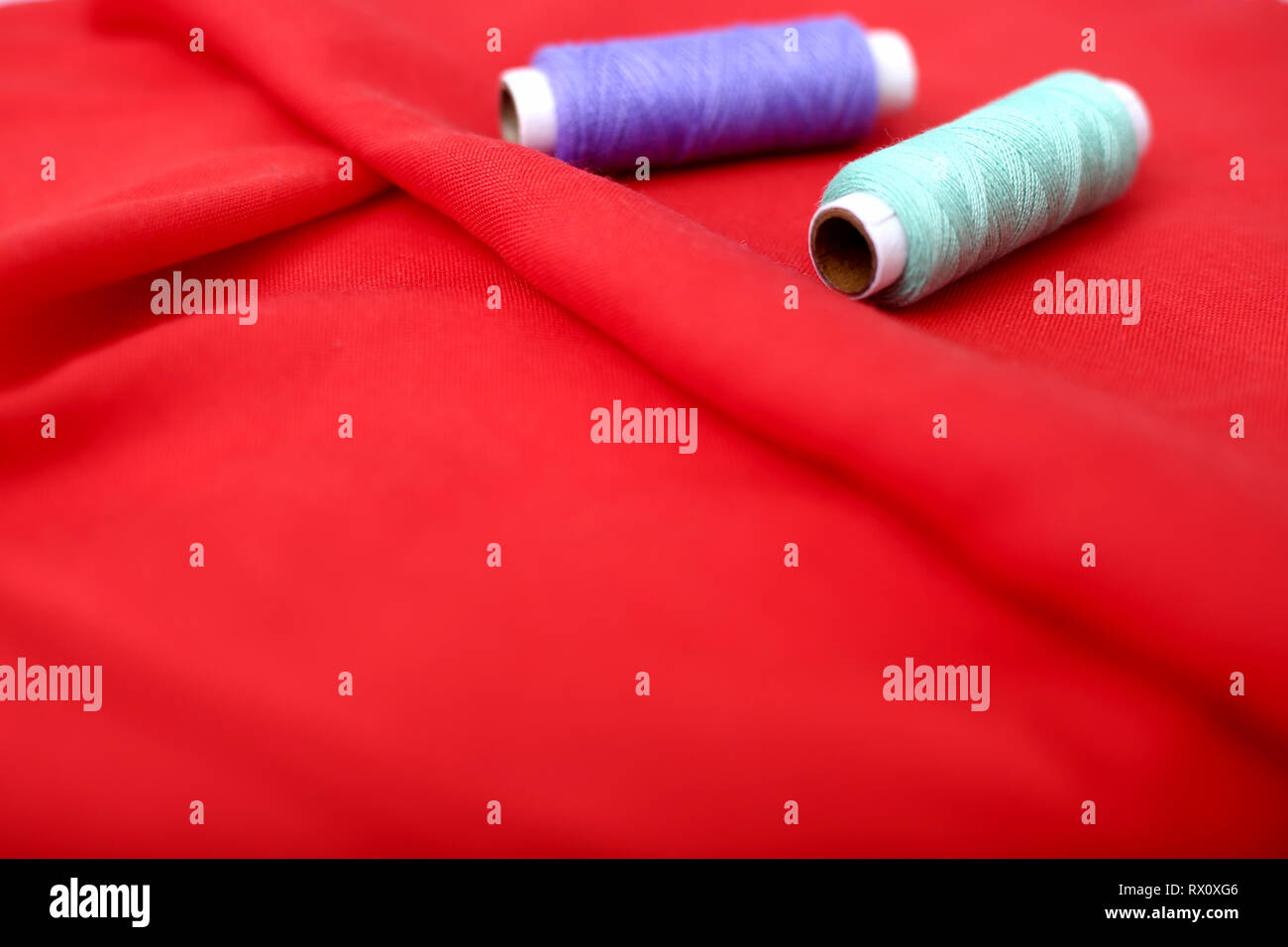 Two sewing thread on the red cloth Stock Photo - Alamy