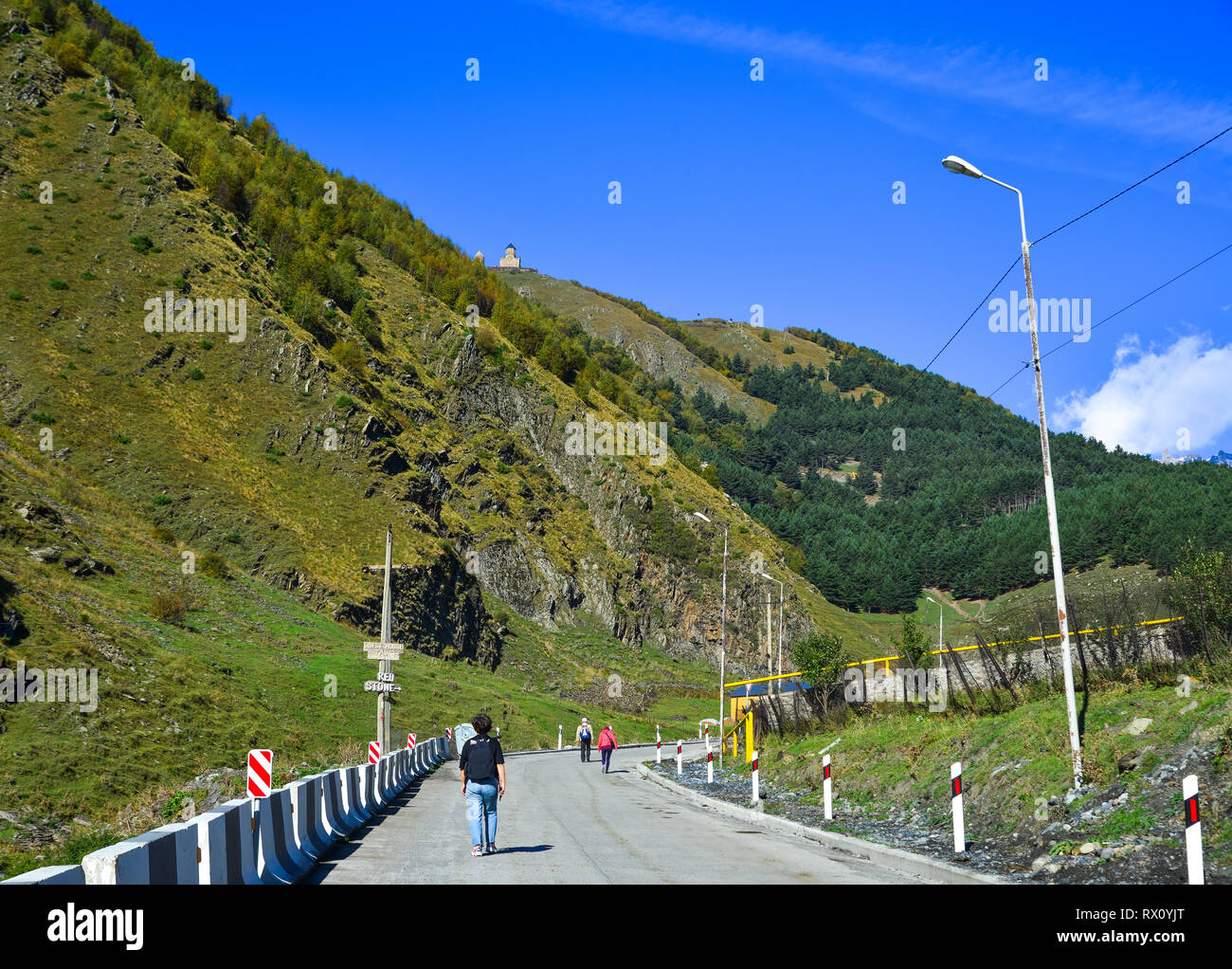 Kazbegi, Georgia - Sep 24, 2018. People walking on mountain road in Kazbegi, Georgia. Stock Photo