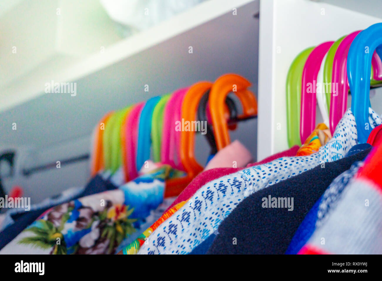 Colorful kid's hangers with toddler boy's shirts hanging in a closet. Stock Photo