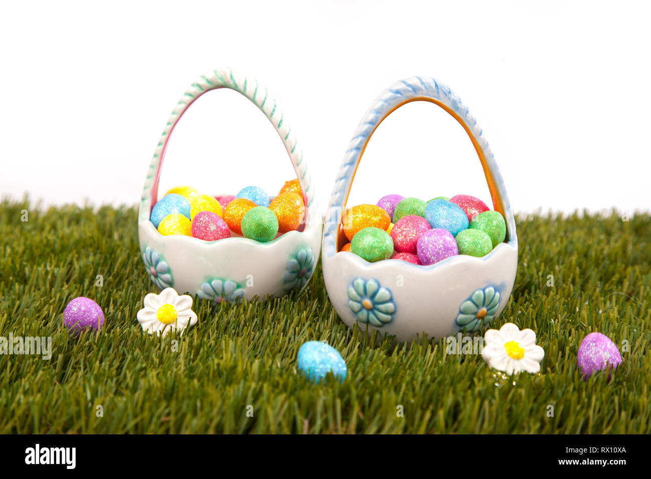 Pair of ceramic easter baskets full of colourful eggs on grass against  white background Stock Photo - Alamy