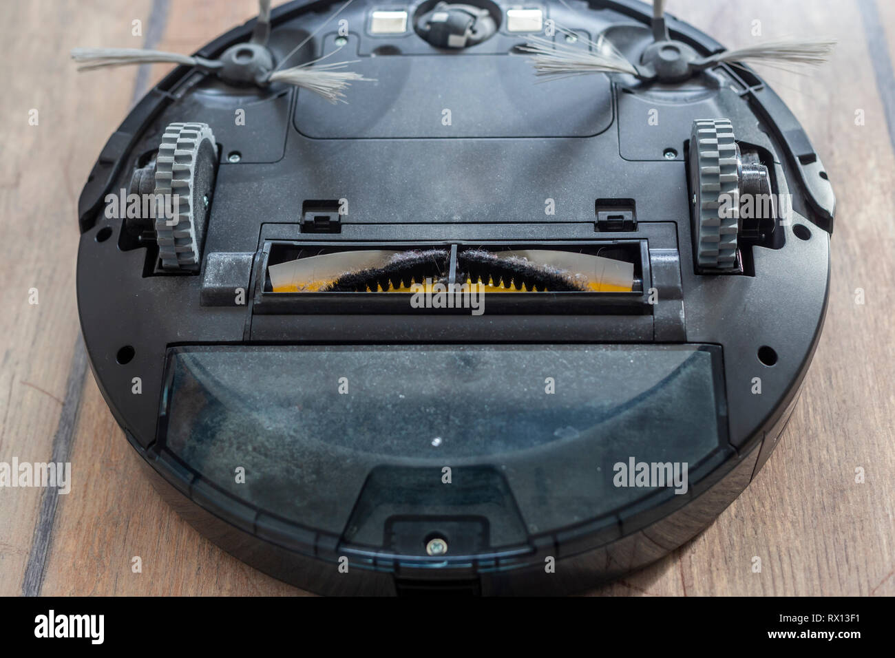 Robot vacuum cleaner upside down on the floor. Covered with dust after cleaning. Stock Photo