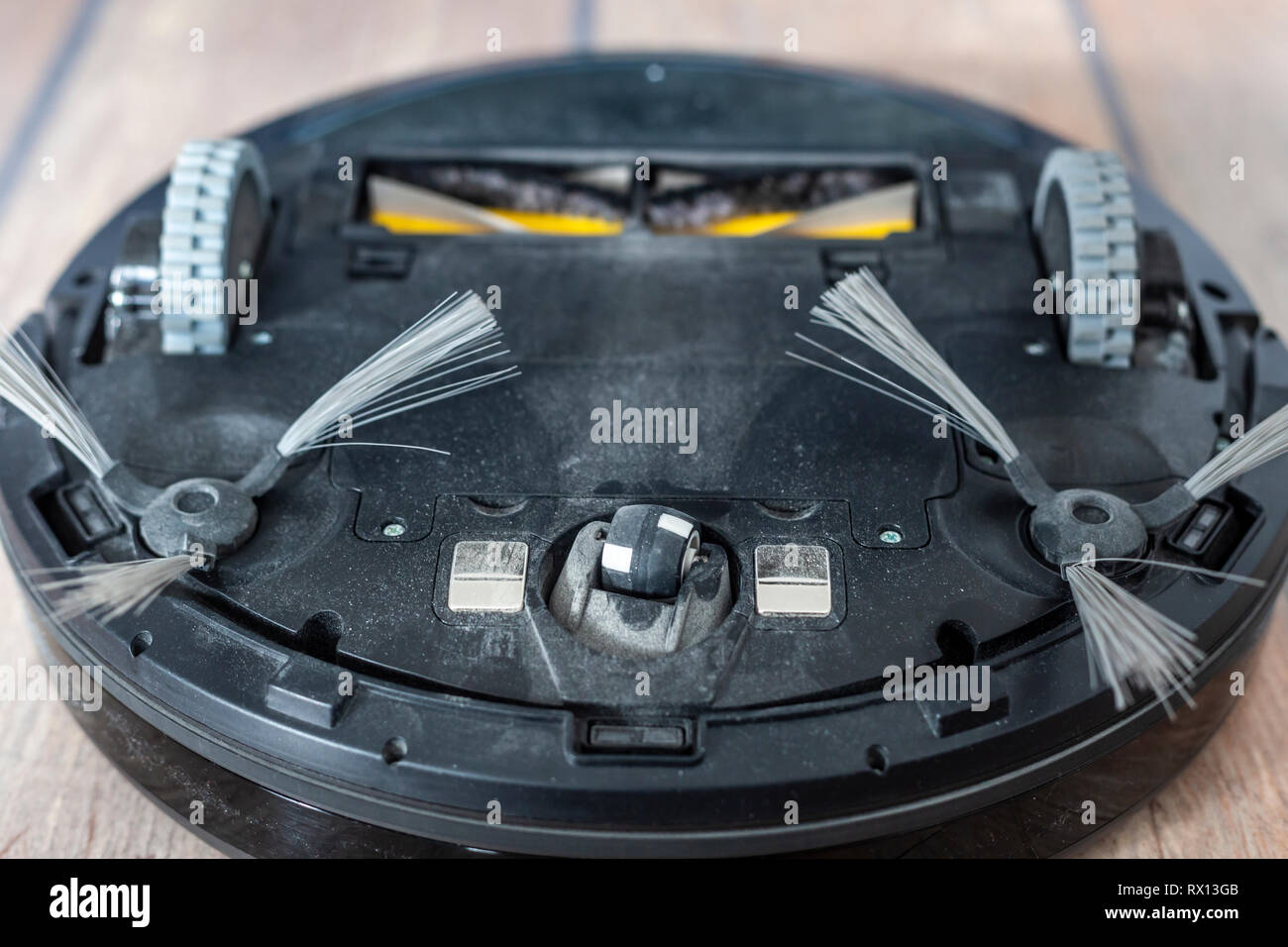 Robot vacuum cleaner upside down on the floor. Covered with dust after
