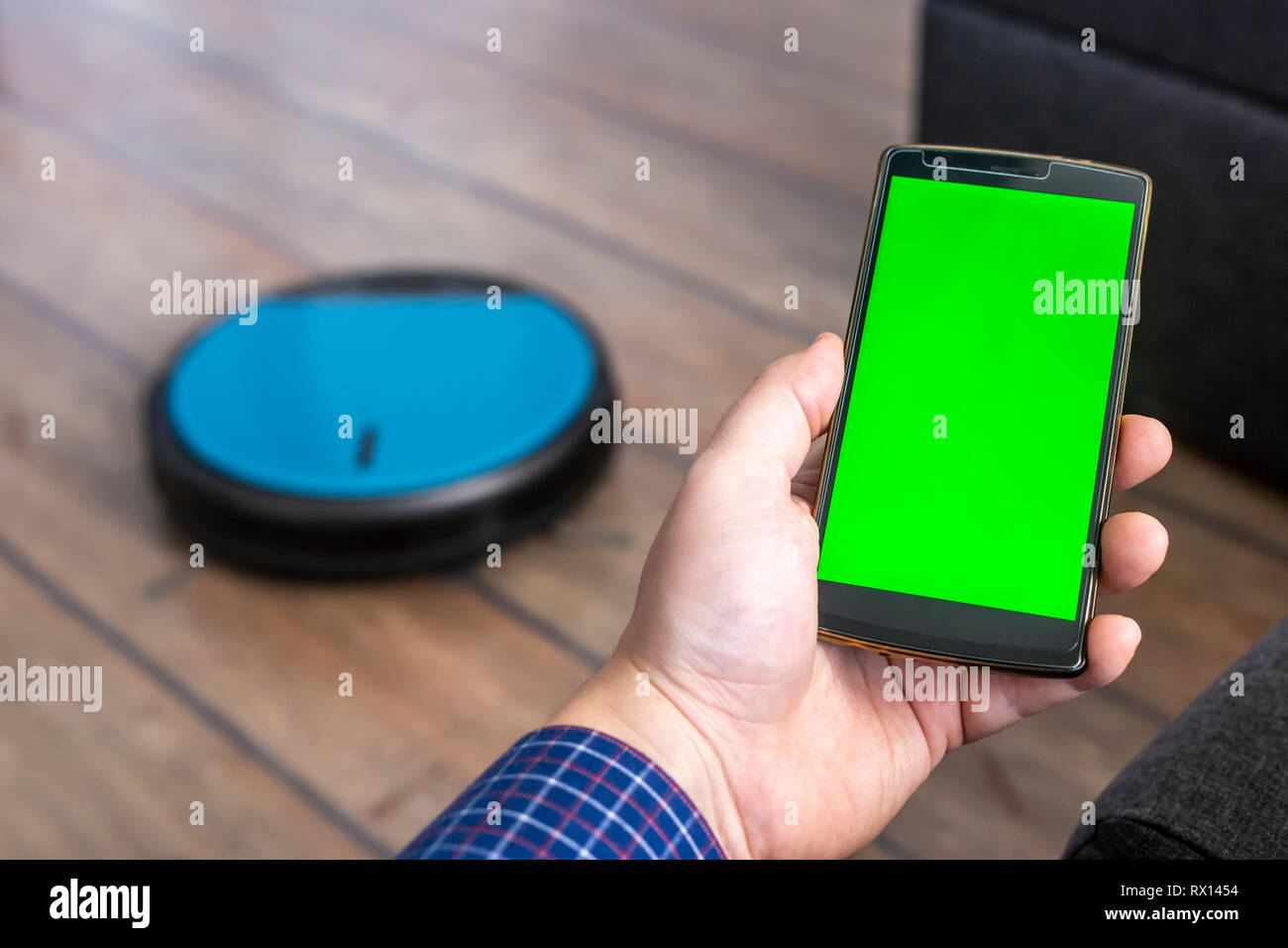 man holding a smartphone and controling a robot vacuum controling