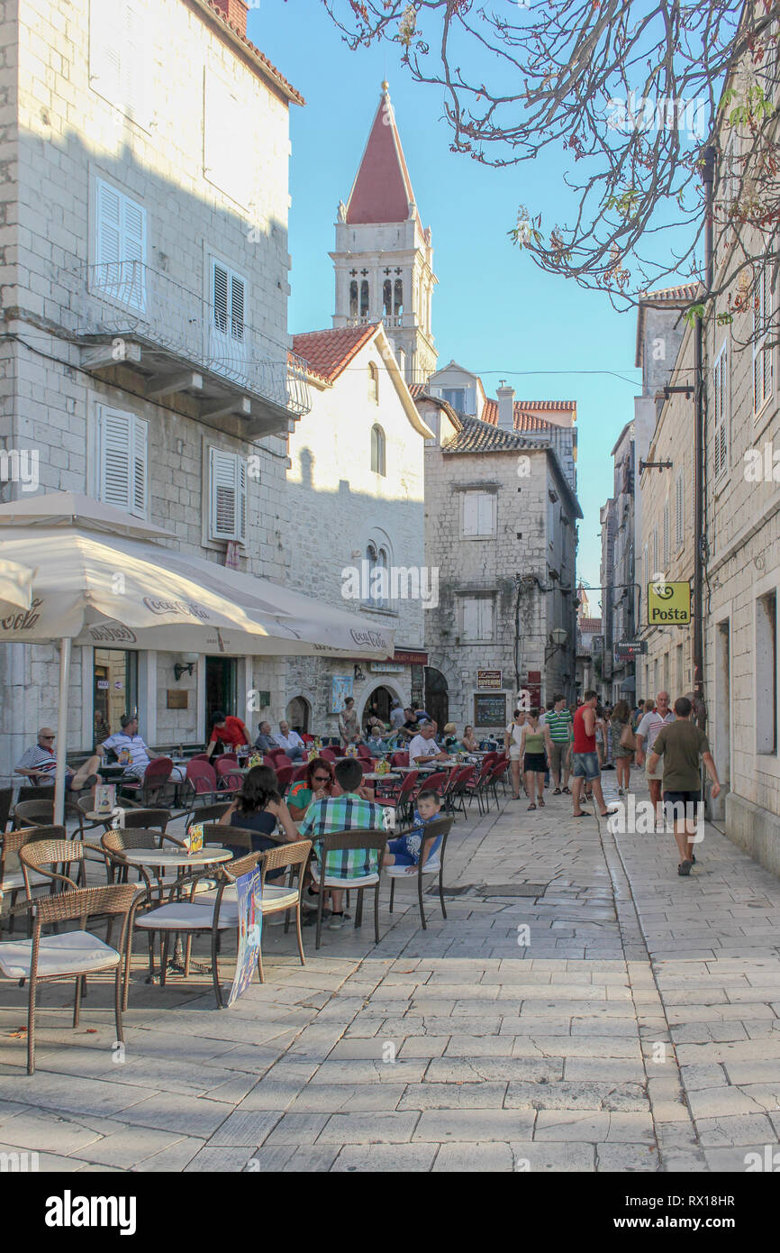 Tourists relax early on a summers evening in the cafe/bars along one of Trogir's ancient backstreets. Stock Photo