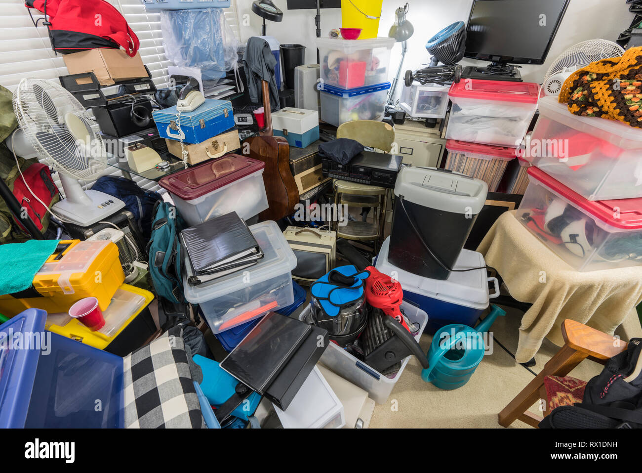 Hoarder room packed with storage boxes, old electronics, files, business equipment and household items. Stock Photo