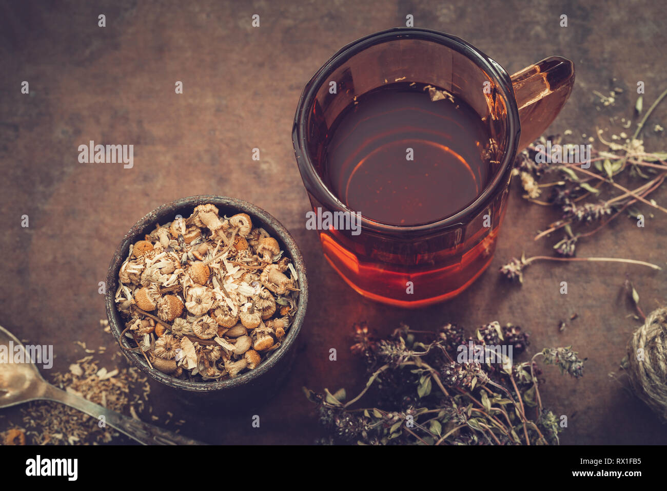 Cup of healthy tea, rustic mortar of daisy herbs, dried thyme on table