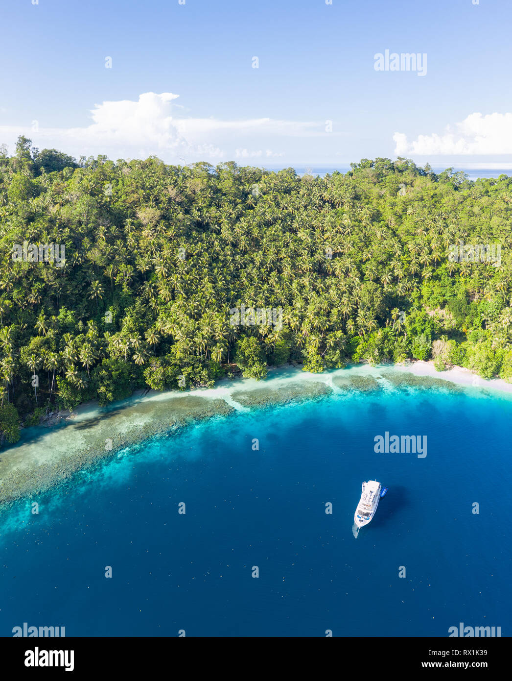 A small dive boat is anchored off the coast of Papua New Guinea. This tropical area is part of the Coral Triangle due to its high marine biodiversity. Stock Photo