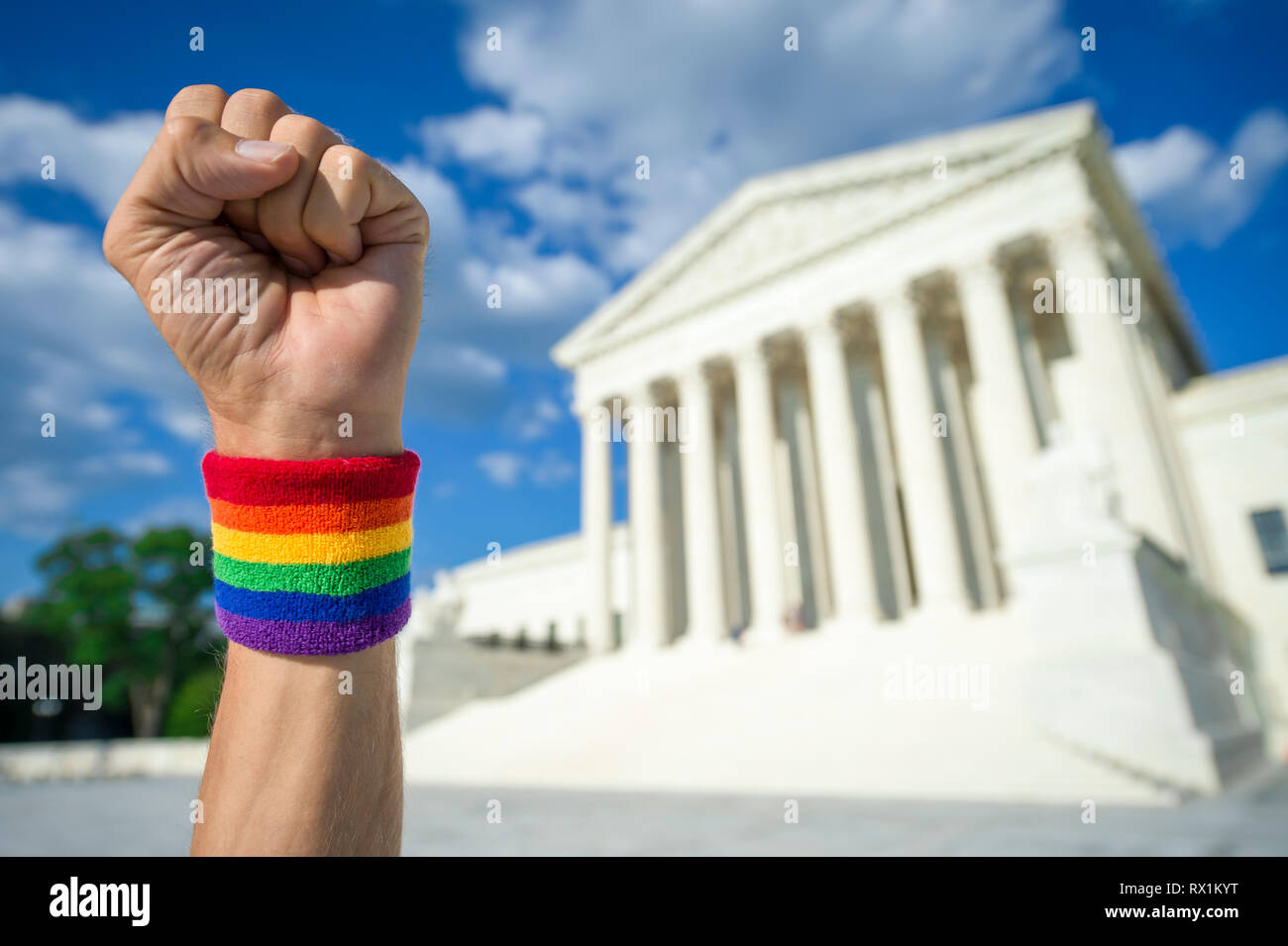 Hand wearing gay pride rainbow wristband making a power fist gesture outside the Supreme Court building in Washington, DC, USA Stock Photo