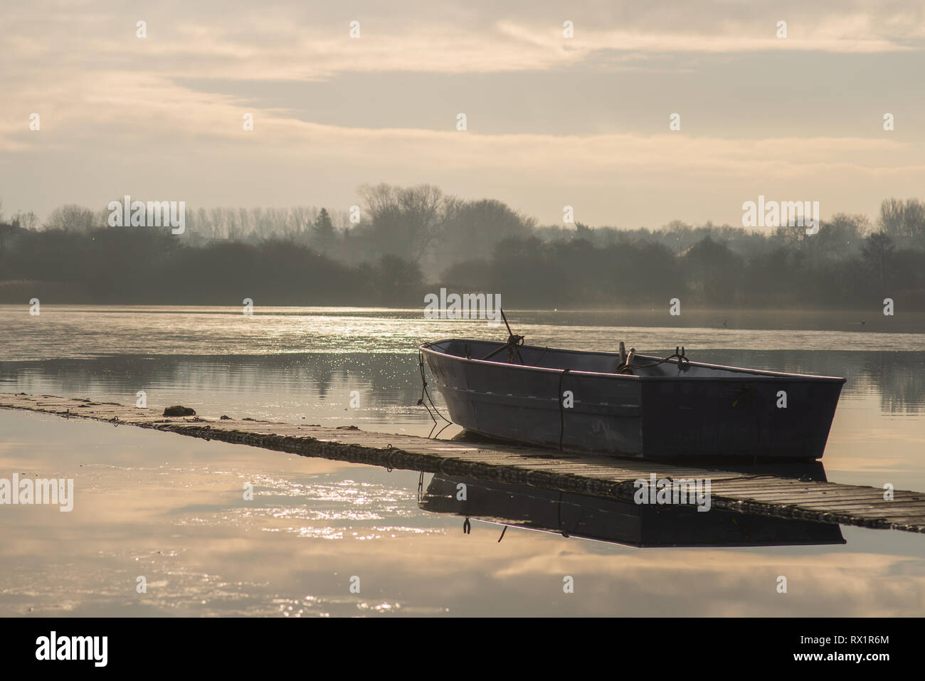 A lone unmanned boat sits idle on a frozen lake during sunrise on