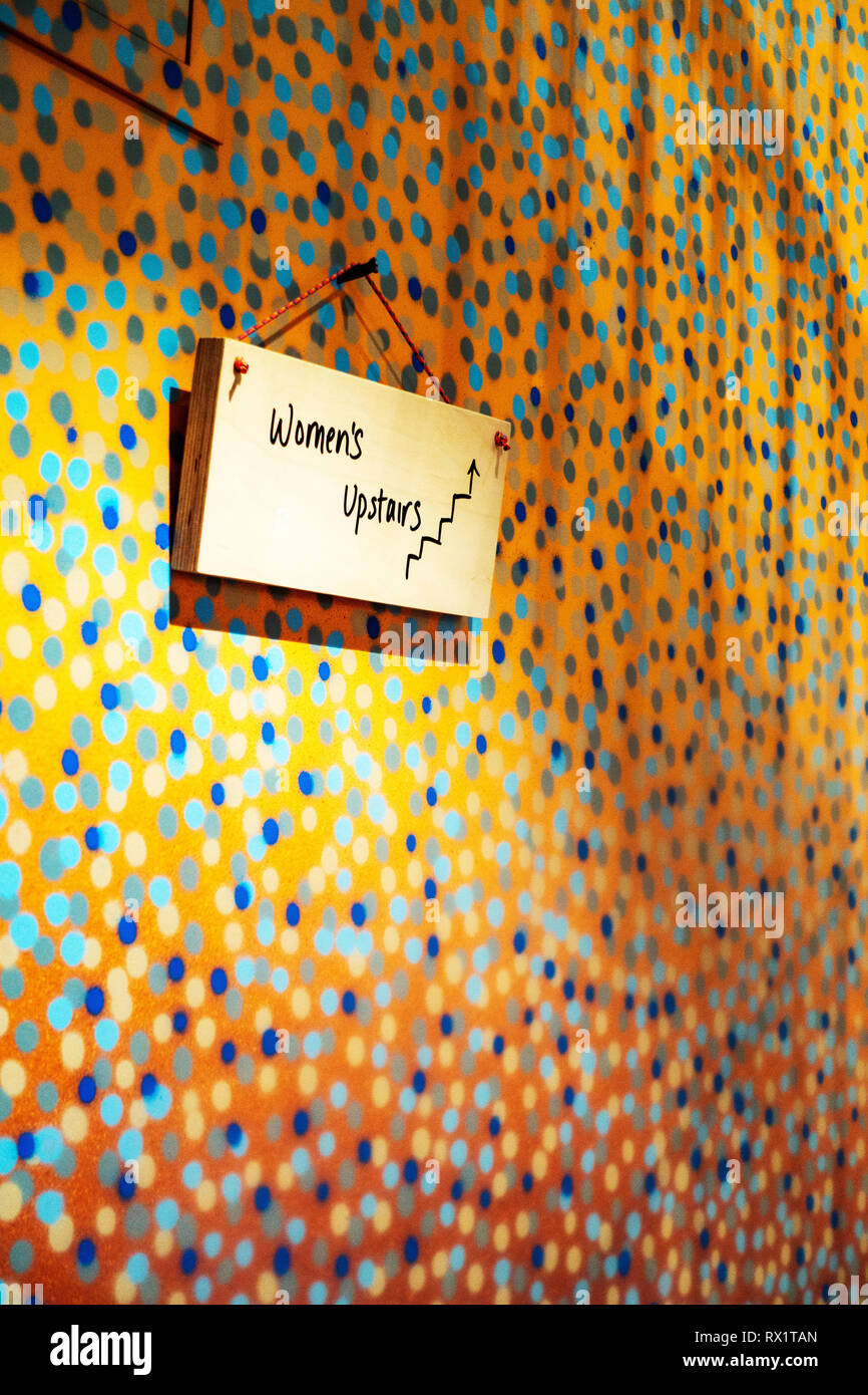 Closeup of a Small hand written sign saying Womens Upstairs hanging on the  bespoke spotted wall in a Paul Smith shop in Covent Garden, London Stock  Photo - Alamy