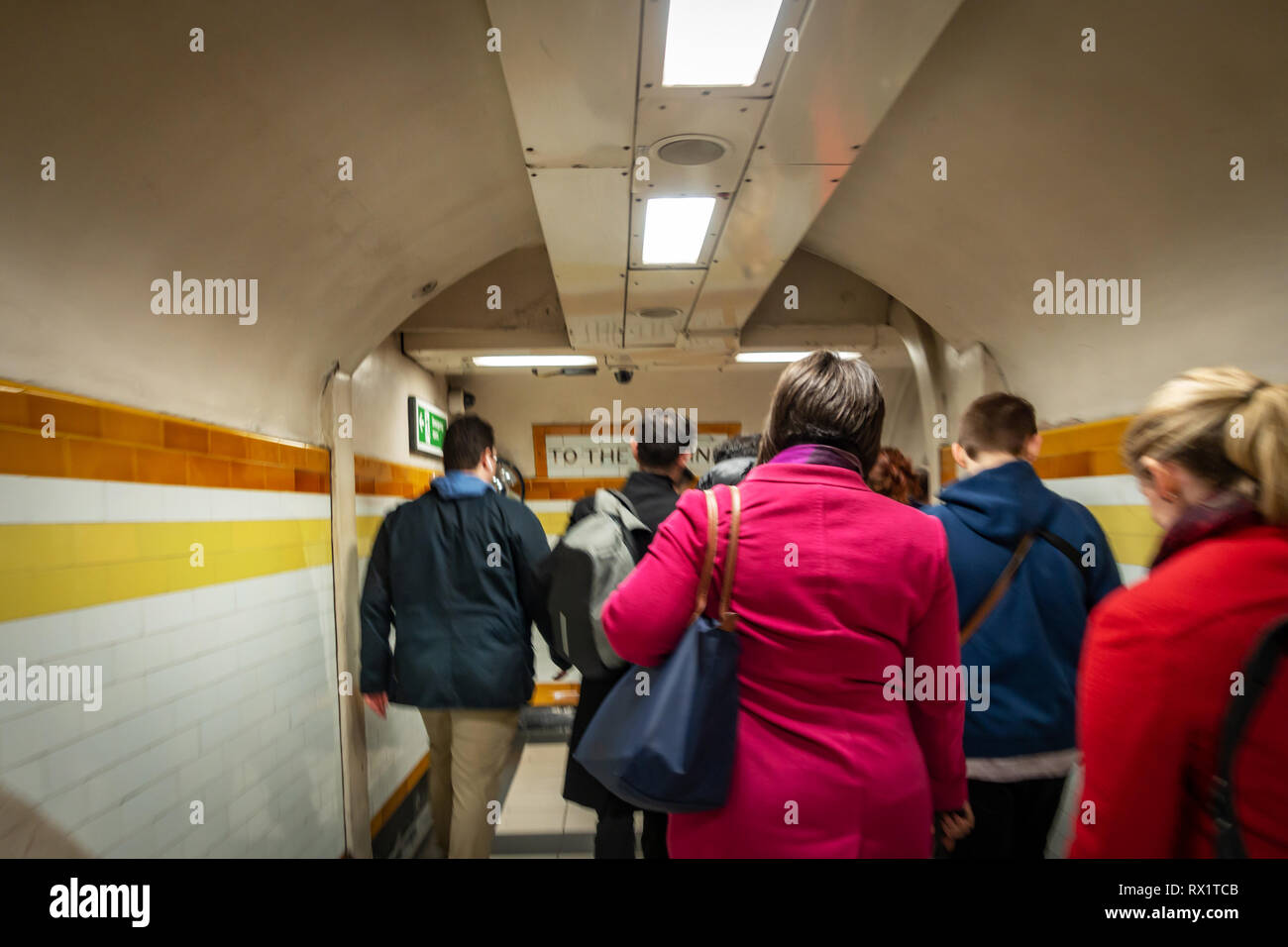 Rear view of Rush Hour Underground Tube commuters time as they travel down the stairs and passageways leading to the Tube in London Stock Photo