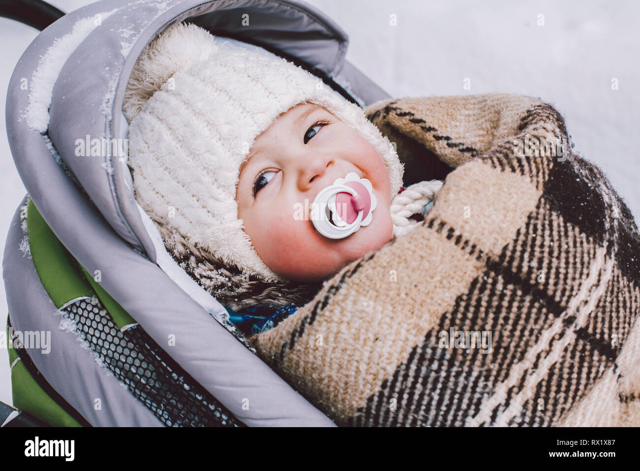 High angle close-up of cute baby boy looking away while lying in baby stroller at park during winter Stock Photo