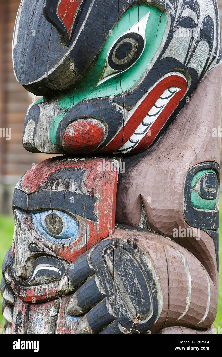 A weathered totem pole depicting Bear stands outside of a residence in the tiny village of Oweekeno.  Rivers Inlet, British Columbia Central Coast, Canada. Stock Photo