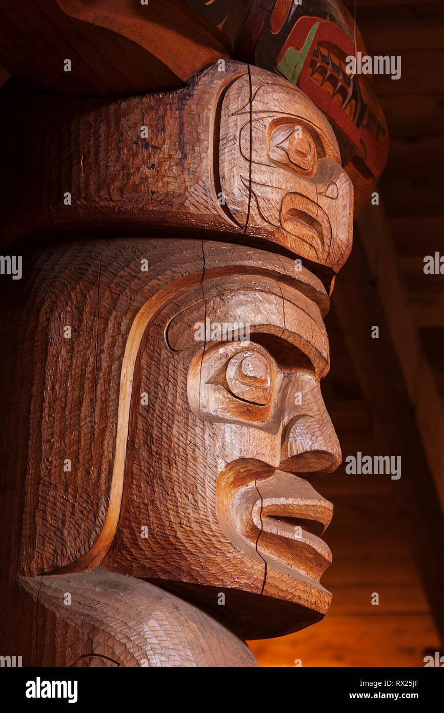 A large large corner post highlights crests and figures relevant to the Wuikinuxv first nations people in their bighouse.  Oweekeno, Rivers Inlet, British Columbia Central Coast, Canada. Stock Photo