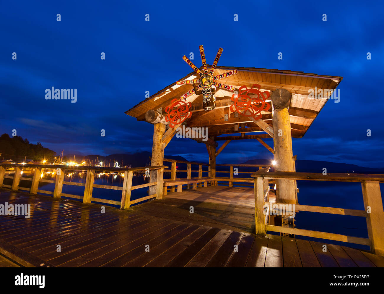 A sun mask dominates the front facade of a shelter along a boardwalk in Alert Bay, Cormorant Island, British Columbia, Canada. Stock Photo