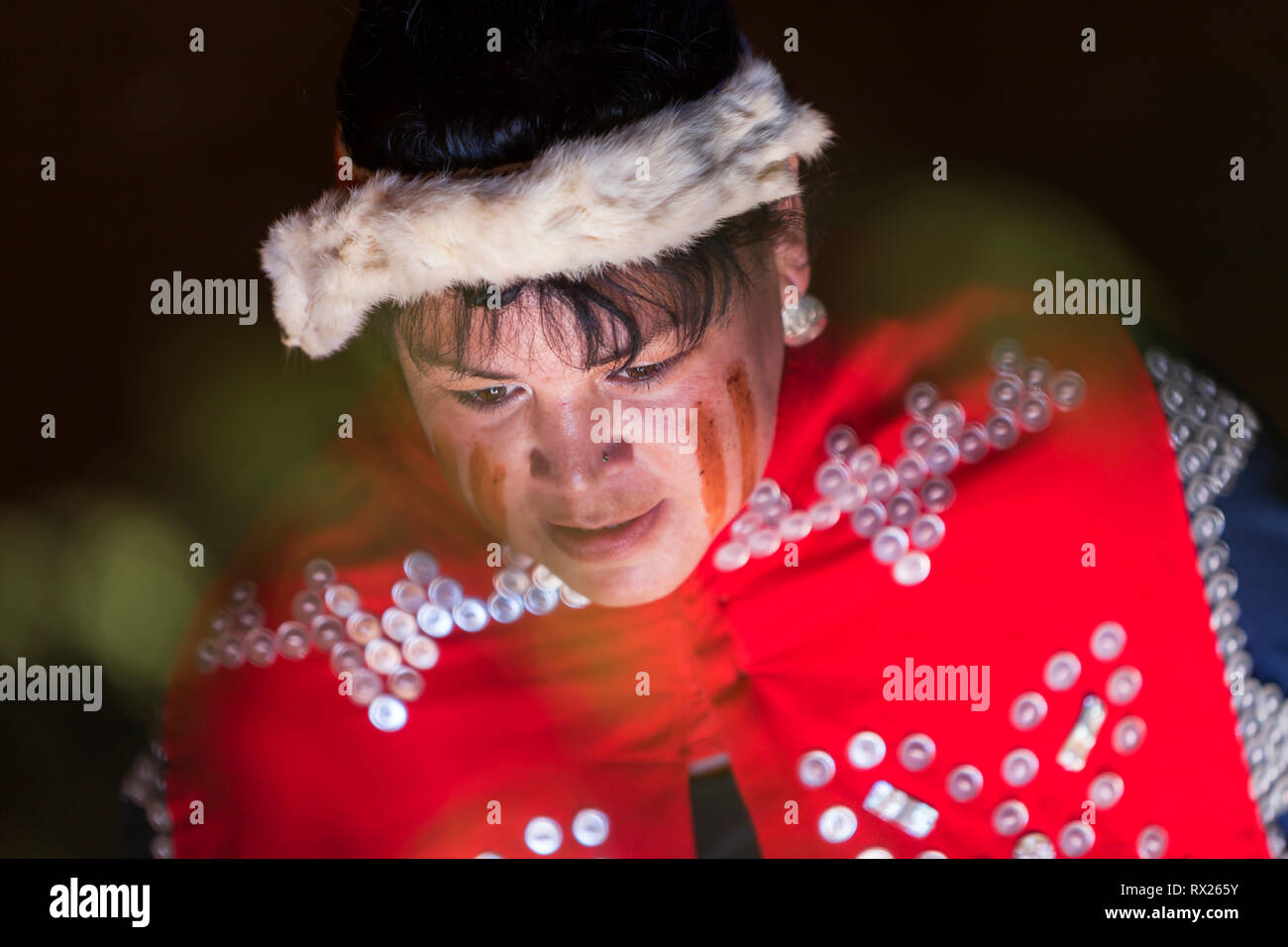 Soft light illuminates the painted face of a first nations woman and her ceremonial regalia, Comox, The Comox Valley, Vancouver Island, British Columbia, Canada Stock Photo
