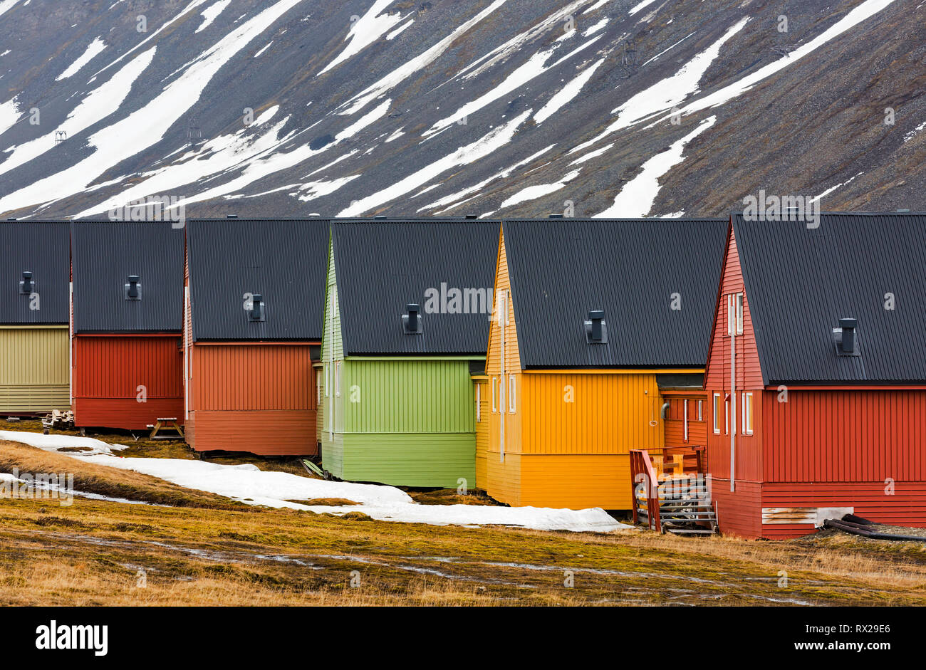 Simply designed row houses contrast with color against a barren mountain background at longyearbyen, Spitsbergan Island, Svalbard, Norway, Scandinavia Stock Photo