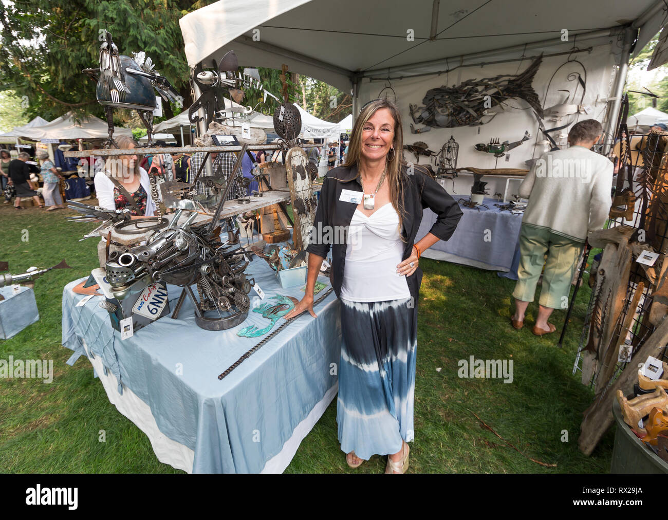 An attractive artisan displays her welding creations at the Filberg Festival, Comox, The Comox Valley, Vancouver Island, British Columbia, Canada Stock Photo