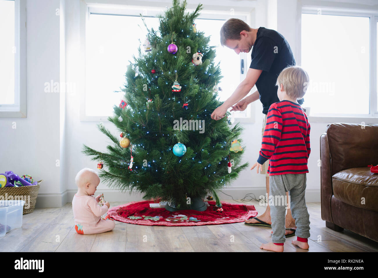 Father decorating christmas tree while standing with children at home Stock Photo