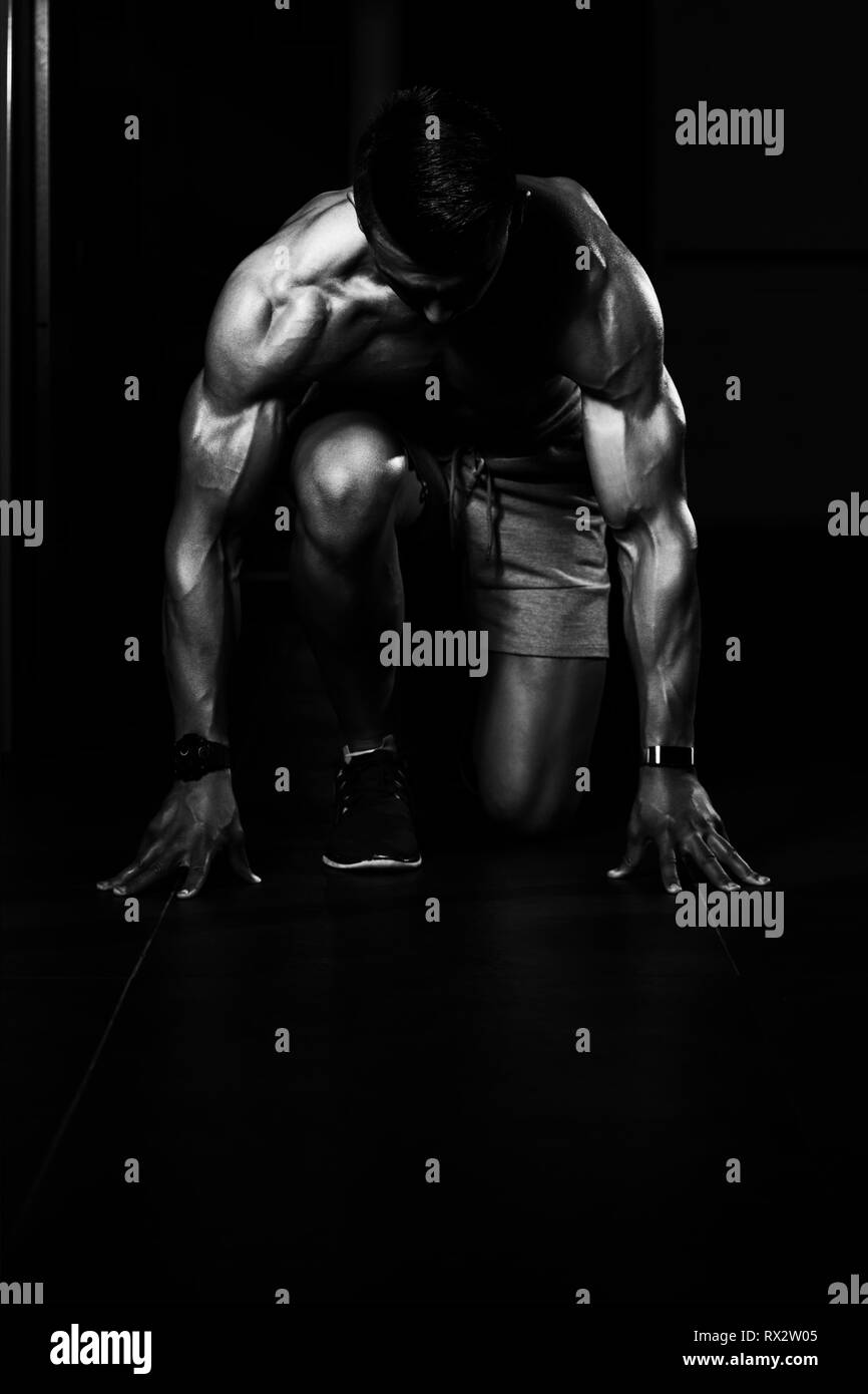Strong Muscular Men Kneeling On The Floor - Almost Like Sprinter Starting Position Stock Photo