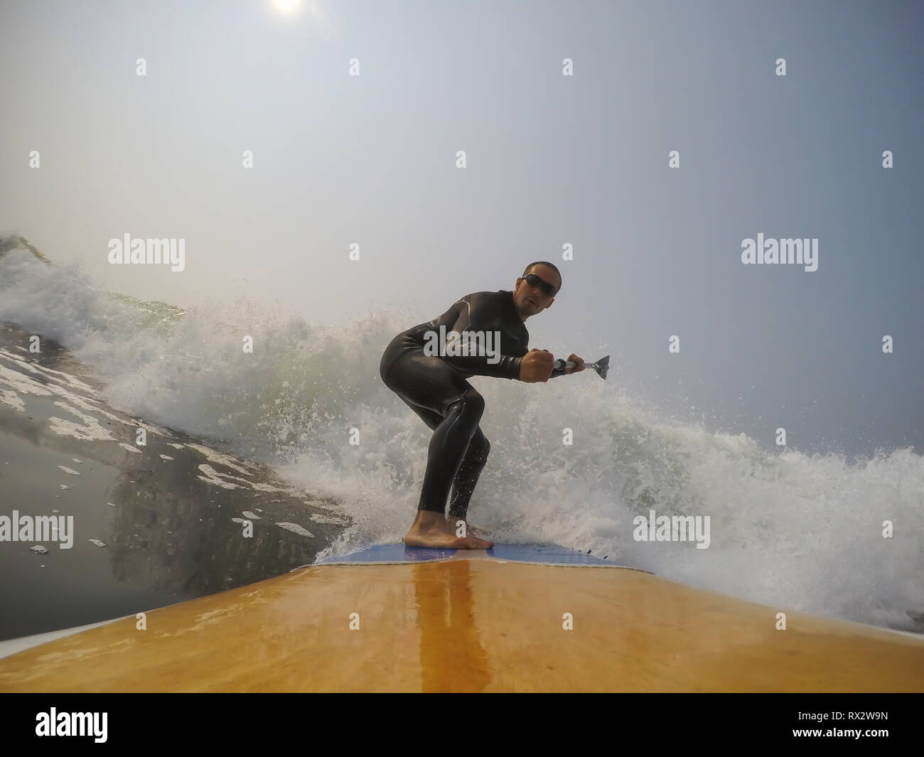 Man paddle surfer is riding a wave in the Pacific Ocean. Taken in