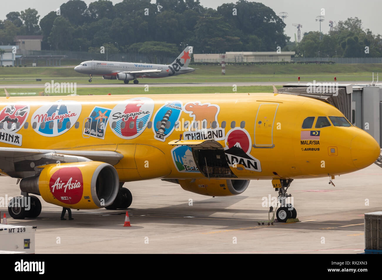 AirAsia Airbus A320-216 airliner in bright yellow livery advertising Expedia travel company at Changi International Airport. Stock Photo