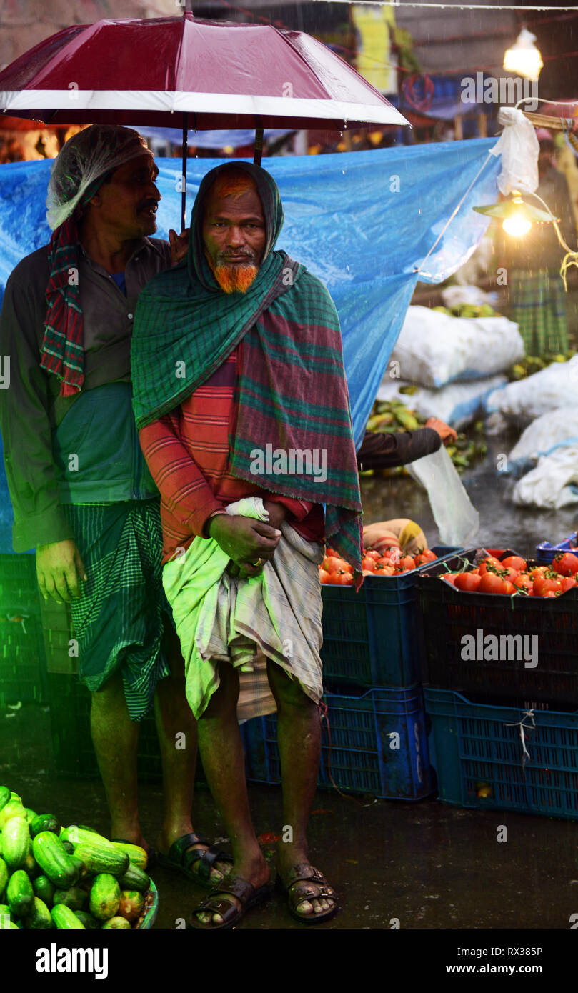 Bangladeshi men under their umbrella at the Karwan bazar in Dhaka. Stock Photo