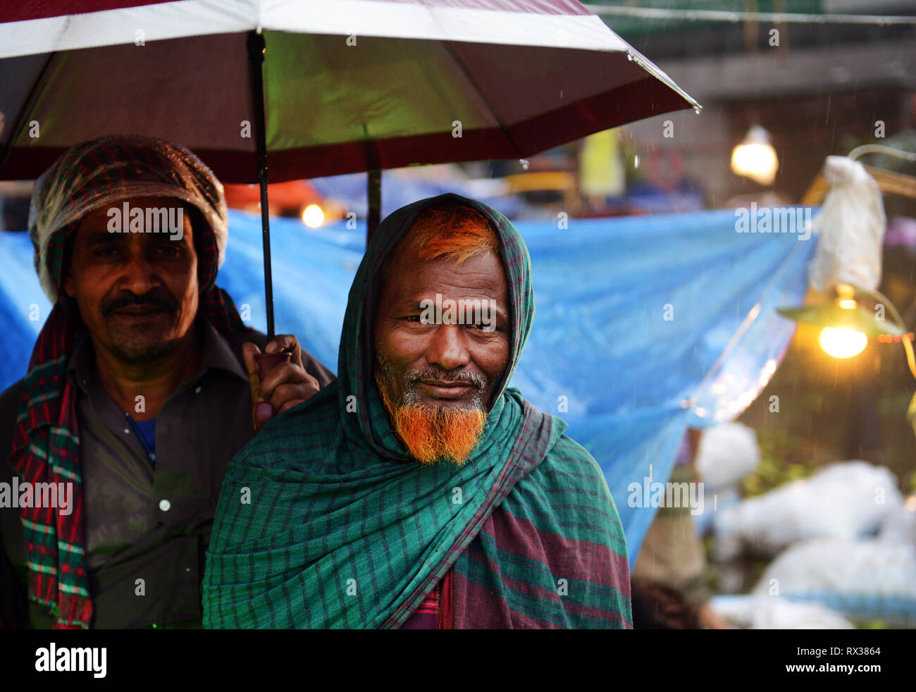 Bangladeshi men under their umbrella at the Karwan bazar in Dhaka Stock