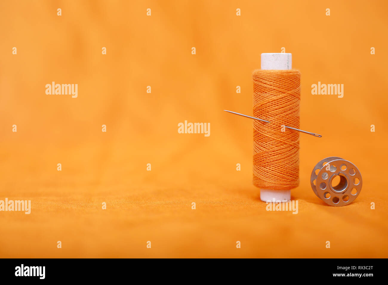 Picture of bobbins and thread with needle . Isolated on the yellow background. Stock Photo