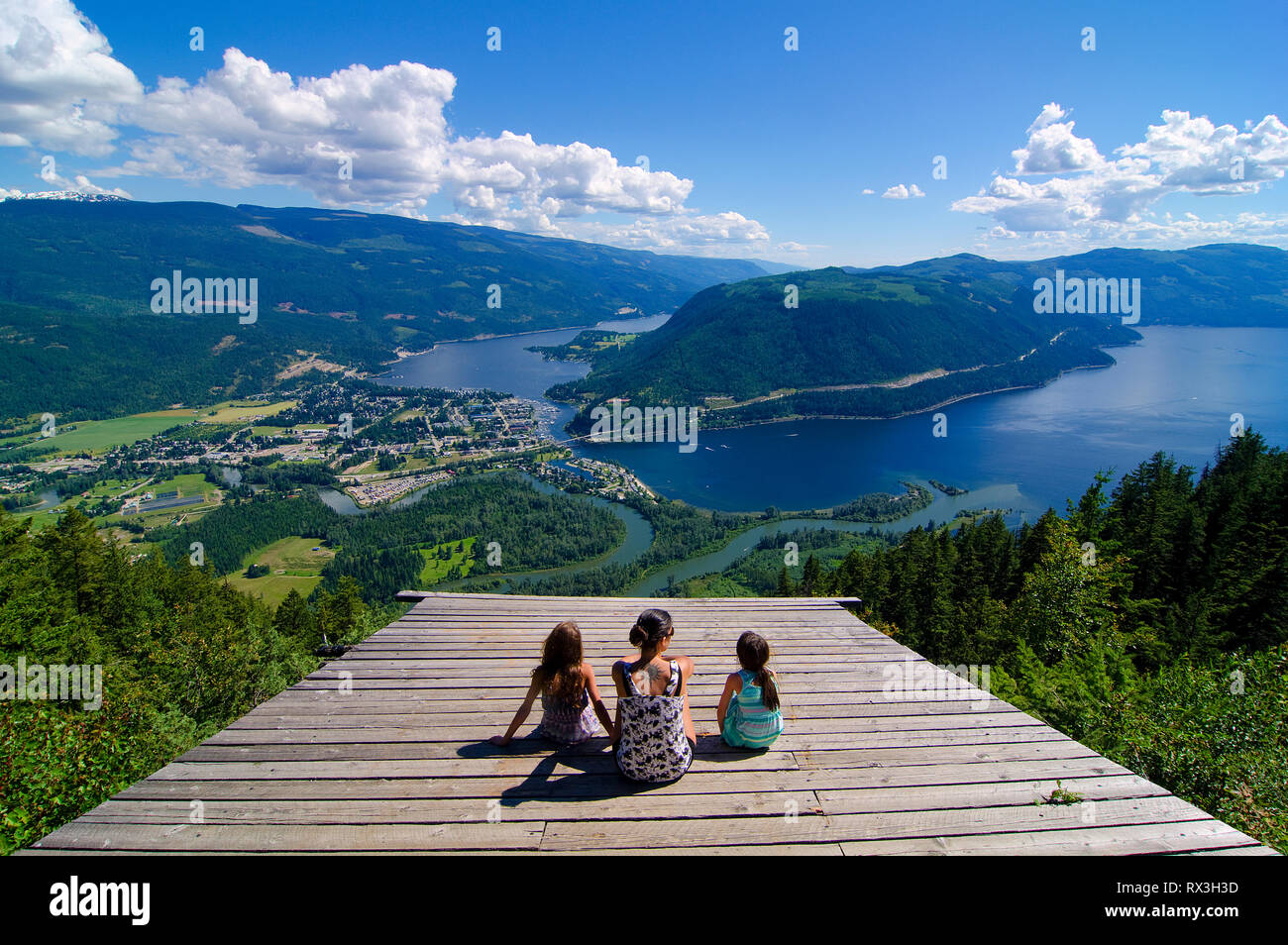 Woman and young girls enjoy an extraordinary summer viewscape from the glider ramp overlooking Sicamous, the Eagle River and Shuswap Lake in British Columbia, Canada Stock Photo