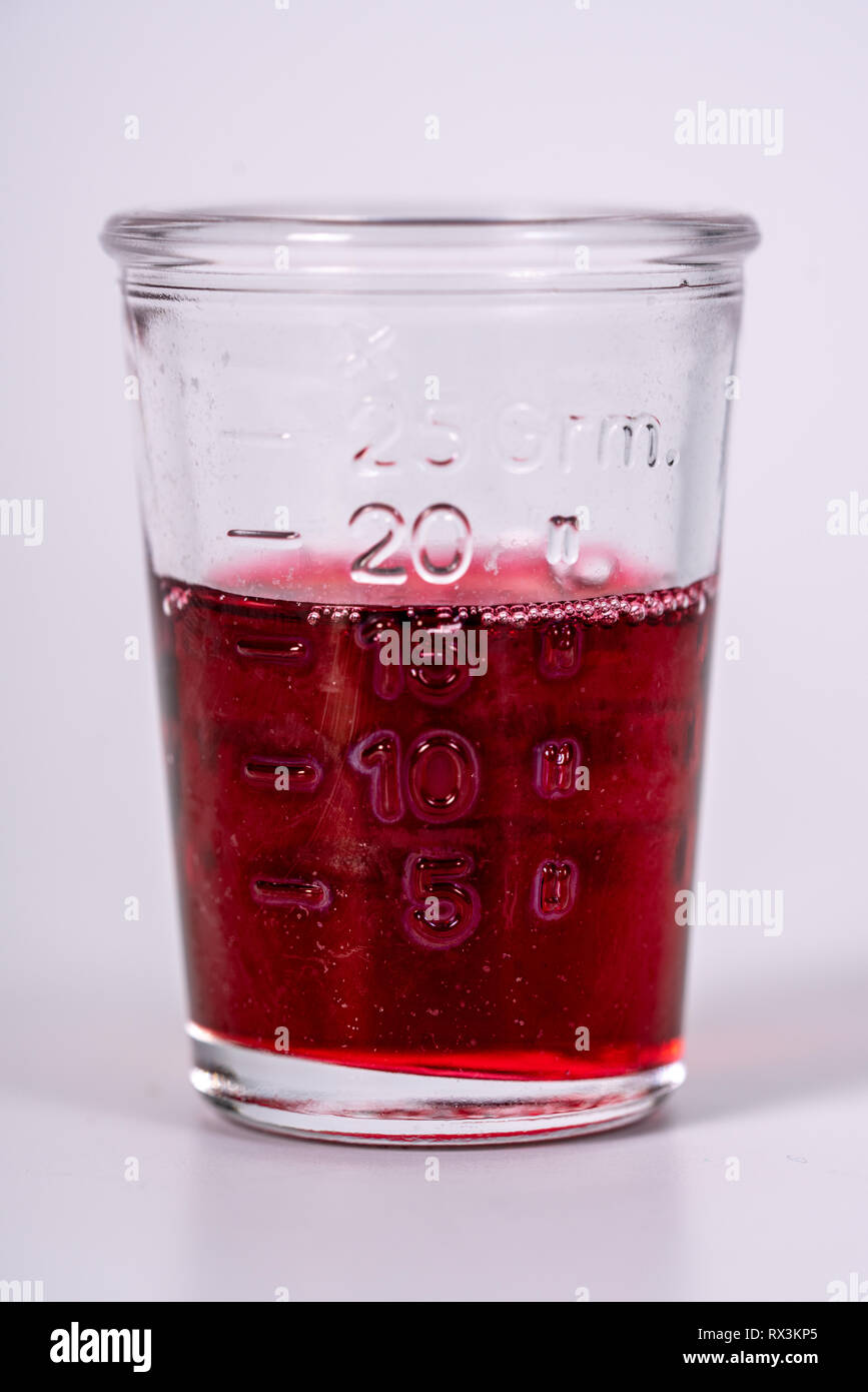 a glass filled with red medicine Stock Photo