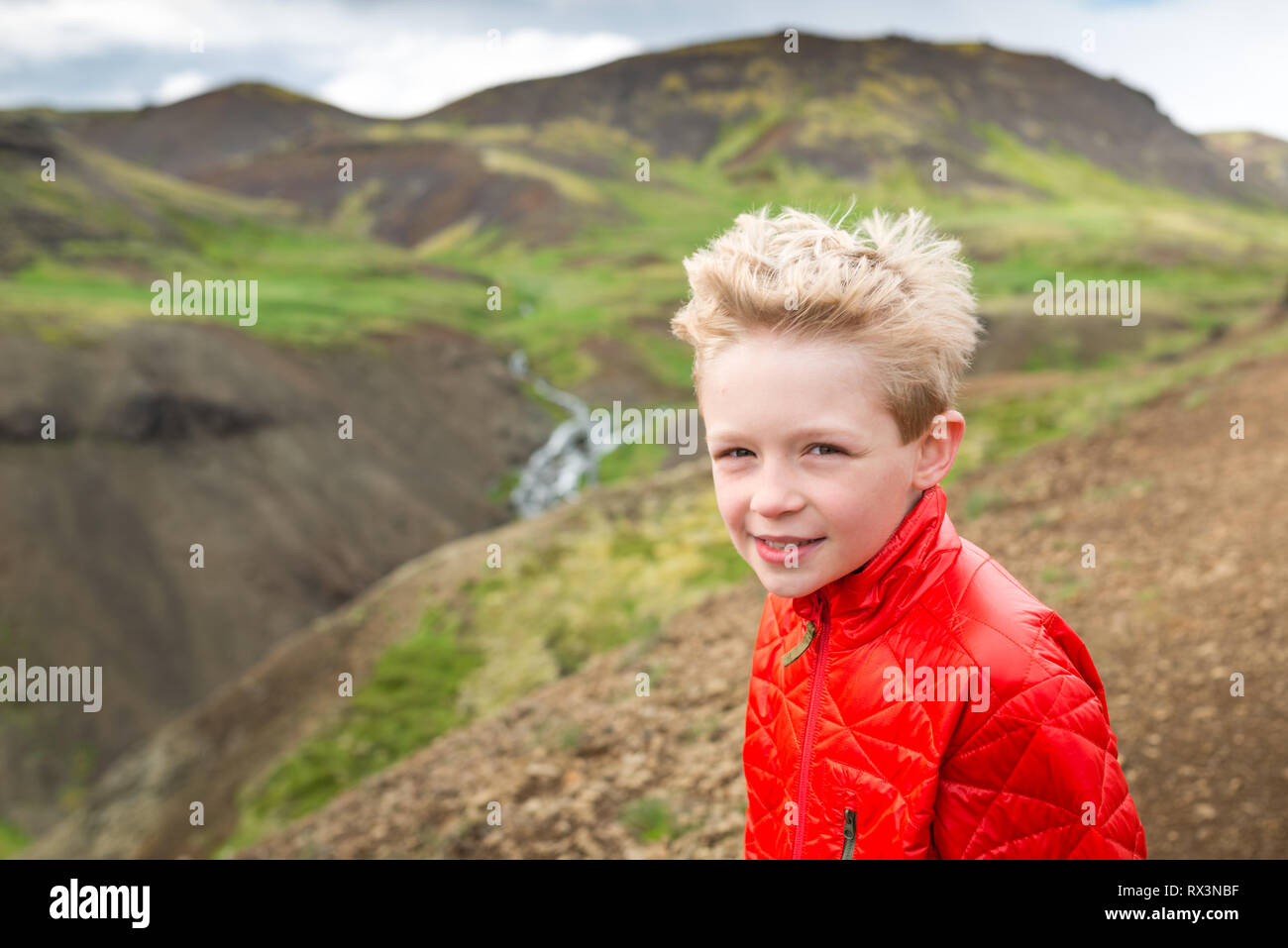 Boy on holiday in Iceland pauses while hiking through valley Stock Photo