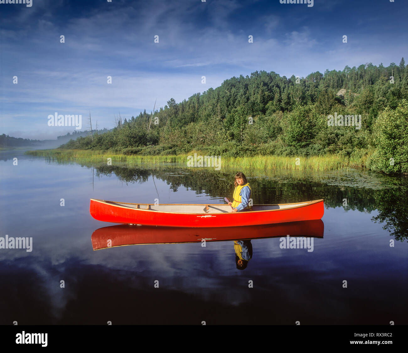 Woman in red canoe on the Montreal River access point to Lady Evelyn Smoothwater Provincial Park, Ontario, Canada Stock Photo