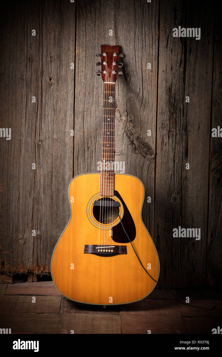 Yamaha acoustic guitar leaning against a wooden barn board wall Stock Photo